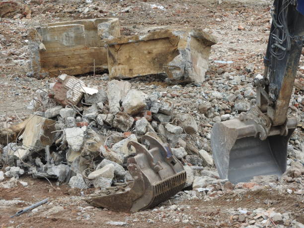 Circular demolition on building site. Machine shovel and excavavator separate concrete, stones steel and sand for recycling.