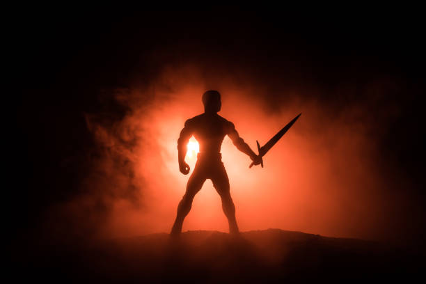 Medieval battle scene. Silhouette of warrior on dark toned foggy background. Night scene. Selective focus