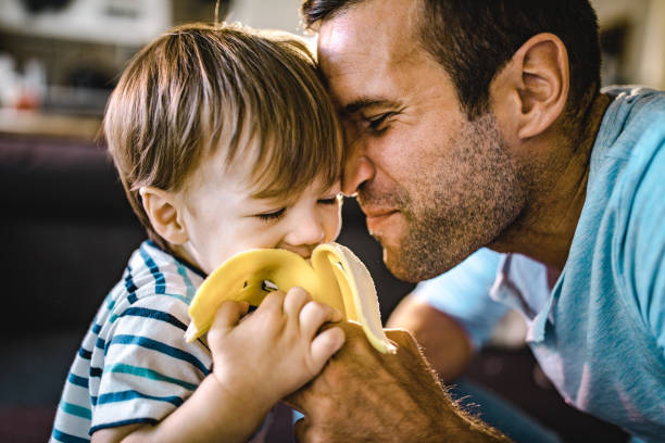 Affectionate father feeding his small boy with banana.
