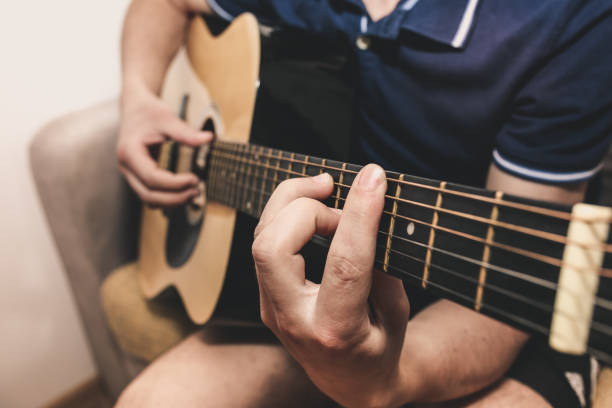 istock Man at home is playing the guitar. Guys hands are taking the chord on strings. Music making lifestyle concept. Free time hobby for everyone. Retro guitar photo. 1096861936
