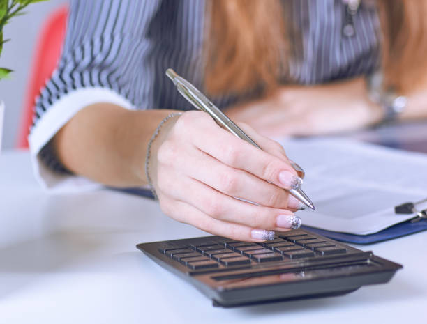istock Business woman hand using a calculator with silver pen in office closeup. 1096863522