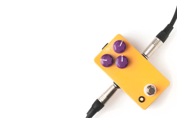 Orange guitar pedal with purple knobs and plugged jacks on white background