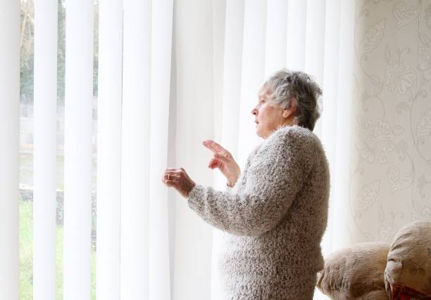 istock Nosey neighbour , senior woman looking through window 1096878554