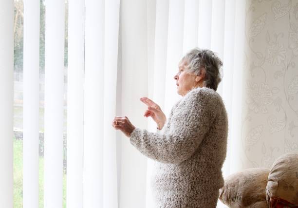 Nosey neighbour , senior woman looking through window stock photo