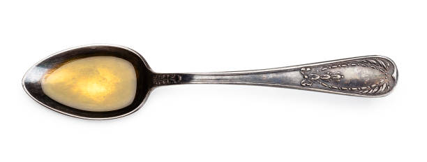 Top view of a vintage metallic spoon with organic olive oil isolated on white background. High key DSRL studio photo taken with Canon EOS 5D Mk II and Canon EF 100mm f/2.8L Macro IS USM.