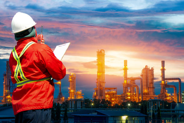 istock Engineering man with white safety helmet standing in front of oil refinery building structure in heavy petrochemical industry, Engineer with oil refinery industry plant background 1096906544