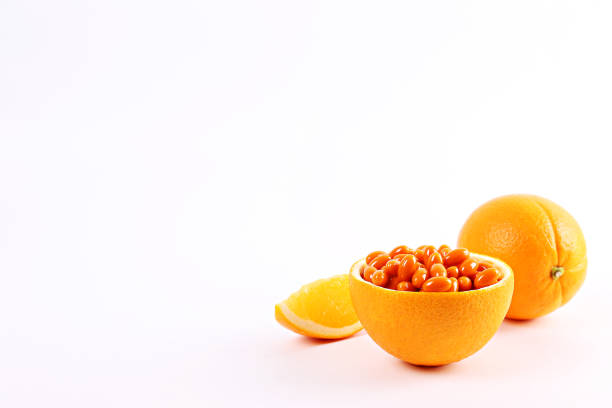 Conceptual image of vitamin c capsules in container made of orange peel. Halved citrus fruit cleaned from pulp core and filled with colorful pills. Background, copy space, close up.