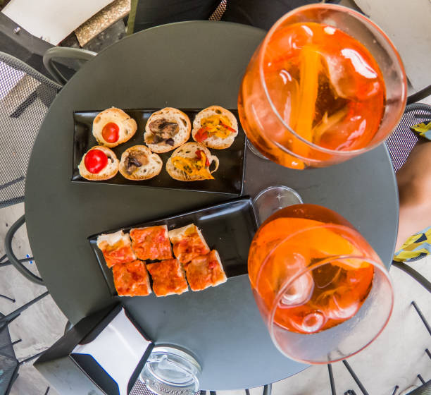 Aperitif on black bar table outdoor. Orange fruit drinks with ice, appetizers. 8473