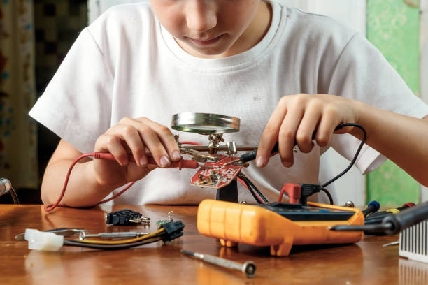 istock The child remotiruet microcircuit. Workplace with soldering iron, microcircuit, magnifying glass, magnifying glass, measuring instruments. Choice of profession. 1096916416