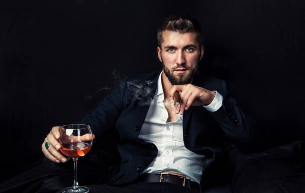 homme d’affaires attrayant avec un cigare et un vieux whiskey - cigar whisky bar cognac photos et images de collection