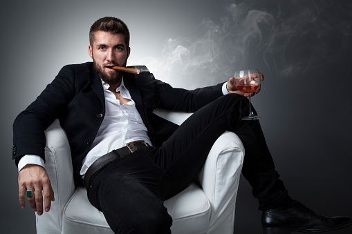 Portrait of an attractive business man with a cigar and a glass of whiskey