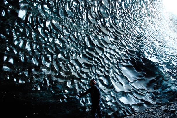 istock Man with Headlamp standing in black ice cave moulin, iceland 1096926732