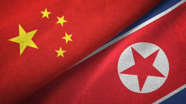 North Korea and China flags together textile cloth, fabric texture