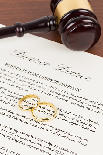 Wooden judge gavel, golden rings, and divorce decree; document is mock-up