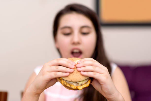 istock Young girl indoors eating a  burger 1096951630