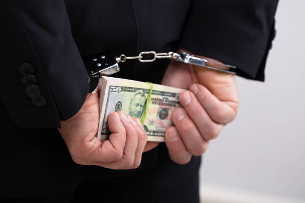 an arrested person holding dollars bill - employee theft imagens e fotografias de stock