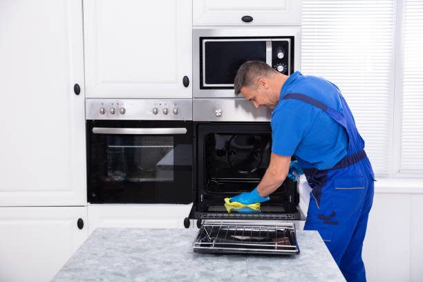 istock Male Janitor Cleaning Oven In Kitchen 1096969784