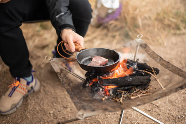 istock Camper cooking steak on a coal burning foldable coal burning barbecue grill in a mini cast-iron pan. 1096970728