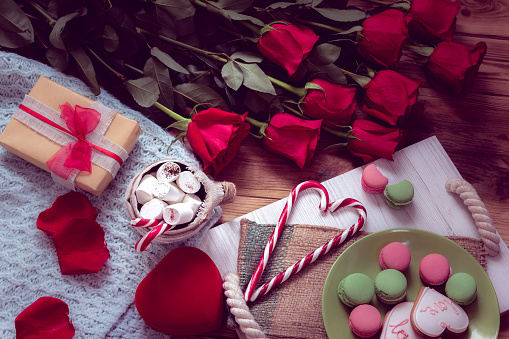 red roses and gifts with breakfast of macaroon and gingerbread cookie on a salver. Still life for St. Valentine's Day