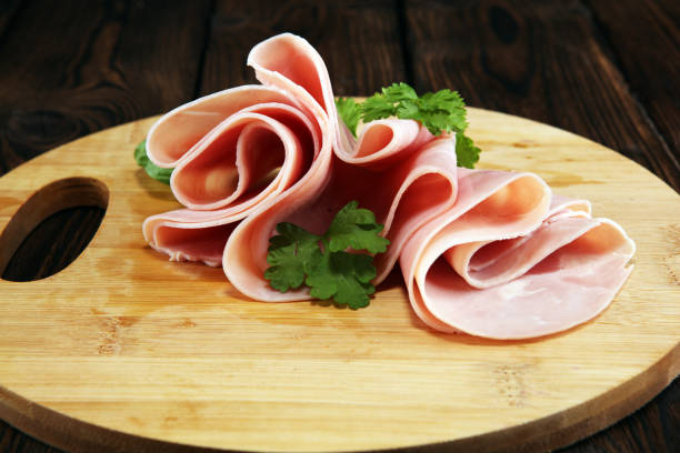 istock Sliced ham with parsley on table. Fresh prosciutto. Pork ham sliced. 1096983240