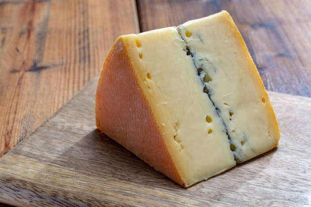 french semi-soft cow milk cheese morbier from franche-comte region with thin black layer and strong aroma - morbier imagens e fotografias de stock
