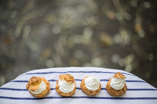 Four choux cream on the table with flower blurred background taken outdoor