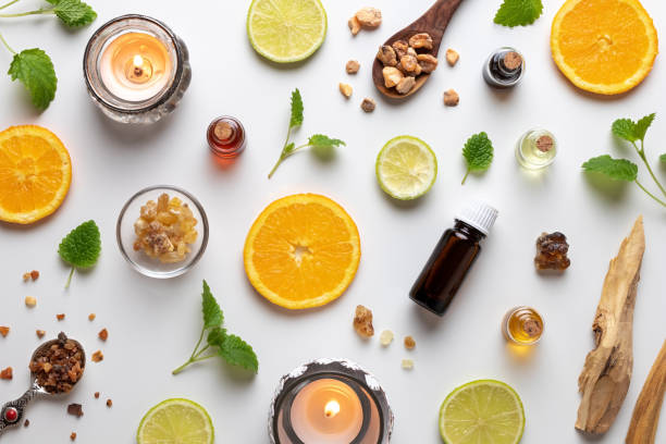 bottiglie di olio essenziale con agrumi freschi, melissa, mirra, sandalo bianco e altri ingredienti - aromatherapy candles foto e immagini stock