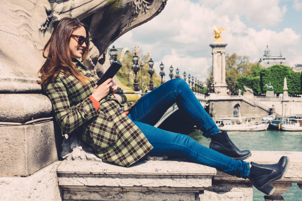 Relaxed woman sitting in the city and reading an e-book