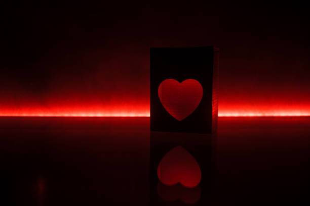 istock Blurred neon heart icon on a dark background. Copy space with red bright colorful heart on black background 1096995810