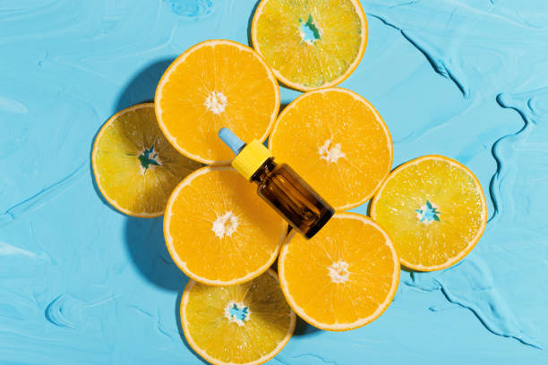 flasche mit ätherischem öl orange, liegt auf frischen orangen - vitamin c fotos stock-fotos und bilder