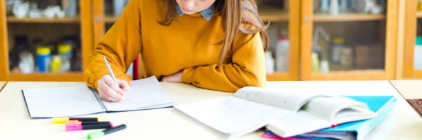 メモを書く化学クラスでの若い女子大生。教室で焦点を当てた学生。本格的な教育概念。 - textbook beauty beautiful caucasian ストックフォトと画像