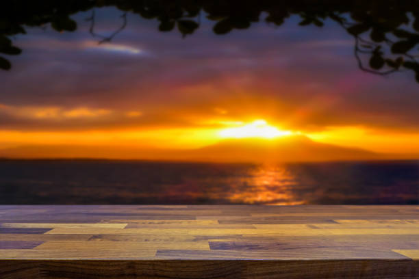Empty table top for product display montage. Tropical paradise island and sunset in ocean blurred in the background.