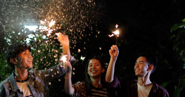 istock Happy Friends Burning Sparklers While Standing Against Sky At Night 1097010930