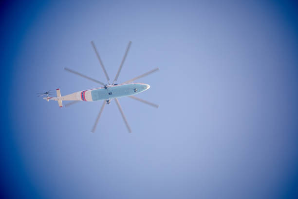 Red helicopter flying into the distant blue sky, above the clouds, and with ample copy space.