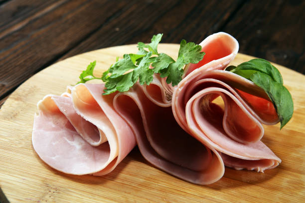 istock Sliced ham with parsley on table. Fresh prosciutto. Pork ham sliced. 1097030138