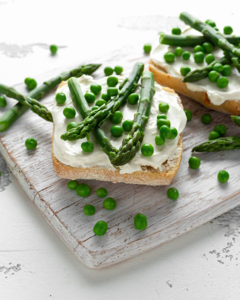 istock Appetizer bruschetta, toast with Asparagus, Peas and creamy soft cheese. on white board. 1097032386