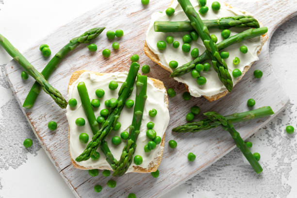 istock Appetizer bruschetta, toast with Asparagus, Peas and creamy soft cheese. on white board. 1097032420