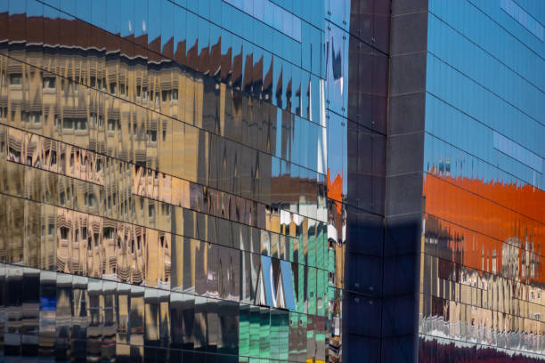 Reflections of buildings in the Black Diamond National library in Copenhagen, Denmark with the quayside in the late afternoon spring sunshine at the side of the canal.
