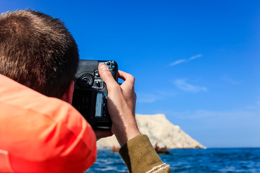 Tourist taking a picture of the Ballestas Islands part of the Paracas District in the Pisco Province off the coast of Peru.