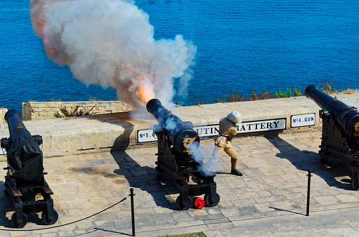 Valletta, Malta - 04 August, 2015: Gunfire at noon in Saluting Battery at Fort Lascaris, view from from Upper Barrakka Gardens in Valletta, Malta