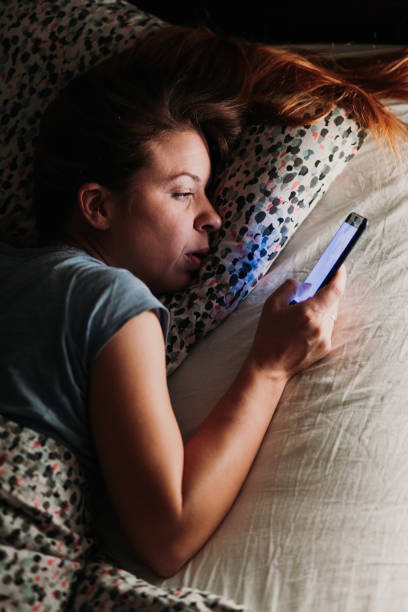 istock Young woman using smartphone in bed at night 1097061570
