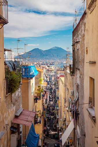 Panoramic view of old street in city of Naples, Campania, Italy with volcano Mount Vesuvius in background, blue sky and white clouds. Europian vacation trip to famous place