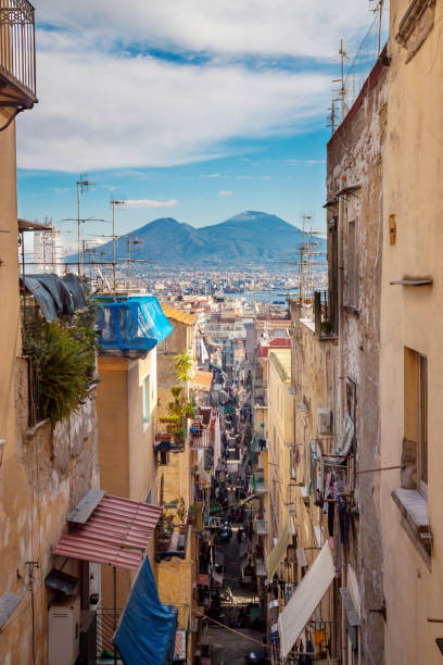 Old street in Naples (Napoli) with view of Vesuvius Panoramic view of old street in city of Naples, Campania, Italy with volcano Mount Vesuvius in background, blue sky and white clouds. Europian vacation trip to famous place naples italy photos stock pictures, royalty-free photos & images