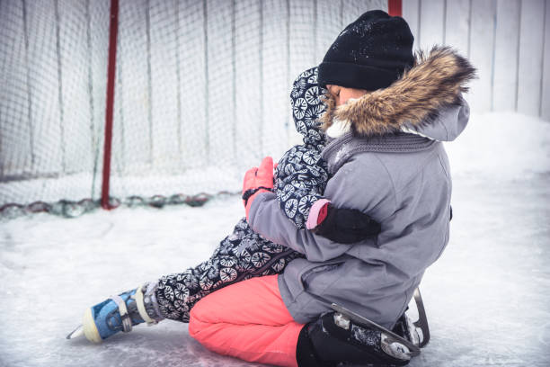 istock Child toddler fall in elder sisters embrace when learning ice skating on skating rink overcoming difficulties through injuries  in a snow park during winter holidays 1097092018