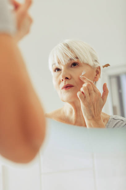 istock Pleasant nice woman applying cream on her face 1097095028