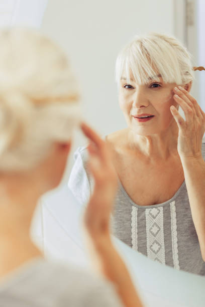 guapa mujer agradable mirando en el espejo - peinados de mujeres mayores fotografías e imágenes de stock