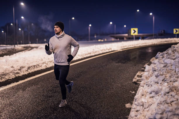 istock Young man running in the city on a cold winter night. 1097098770