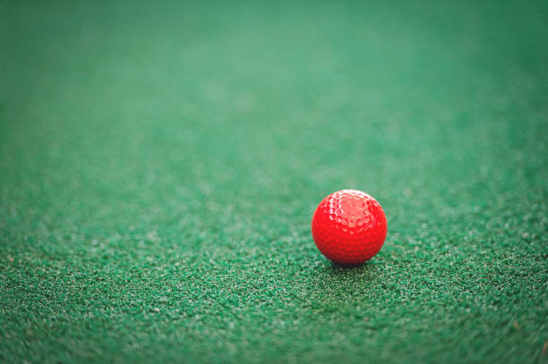 Czerwona piłka golfowa na zielonej murawie – zdjęcie