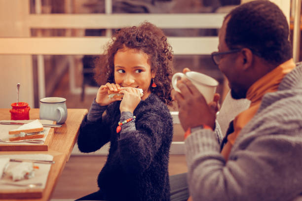 istock Happy man watching his cute daughter eating sandwich 1097113312