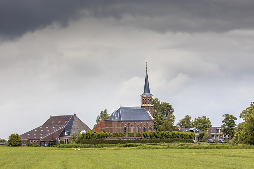 Dutch Hamlet of Warstiens with church and several farm barns in dairy landscape near city of Leeuwarden, Friesland, the Netherlands